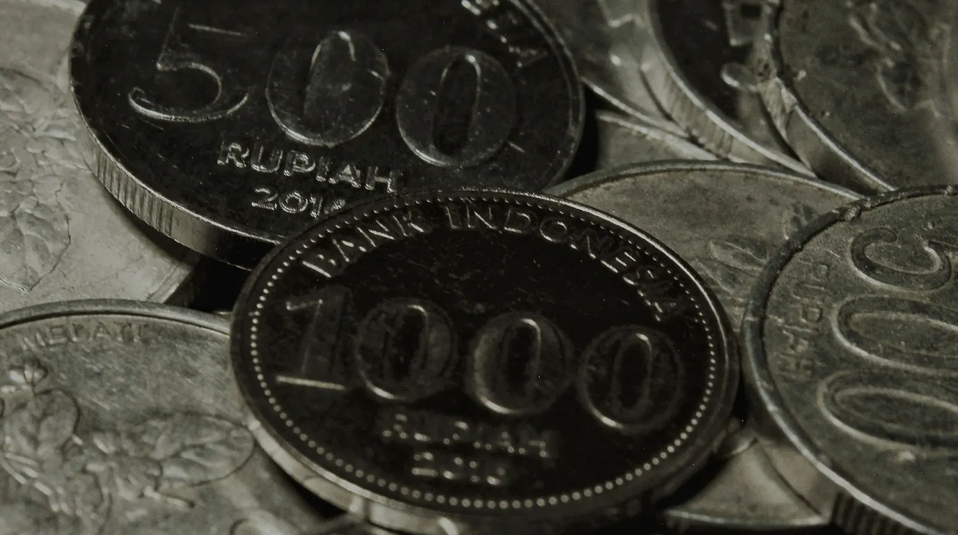 A tight monochrome close-up of overlapping coins stamped with large raised numerals and beaded rims.