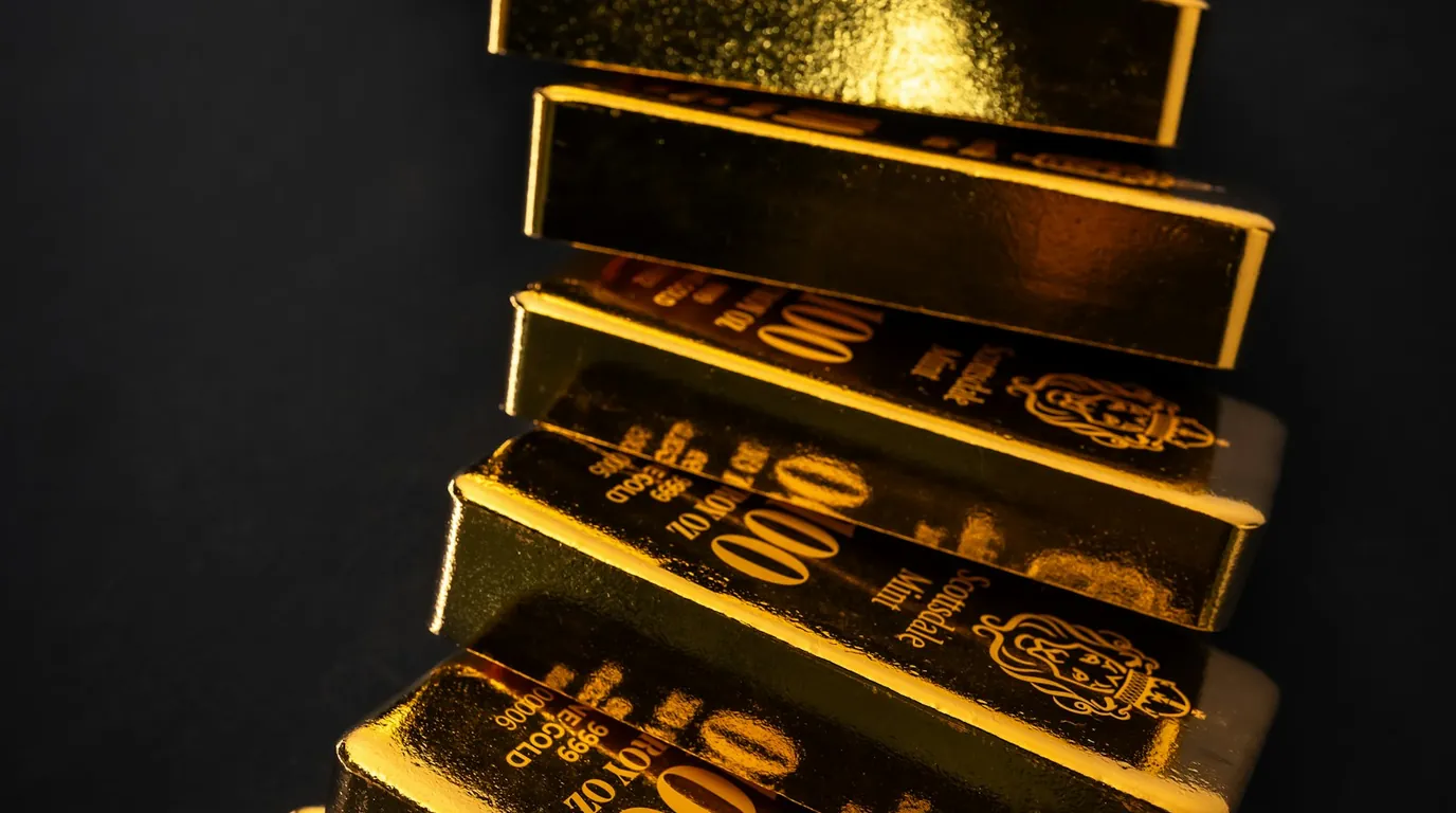 A staggered stack of stamped gold bullion bars on a dark background.