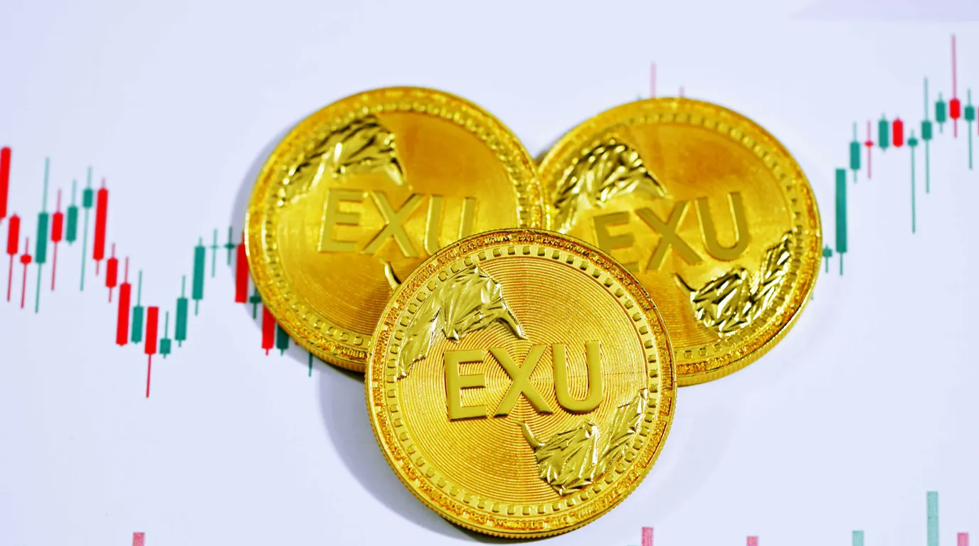 Three shiny gold coins with wreath detail overlapping on a white sheet printed with red and green candlestick bars.